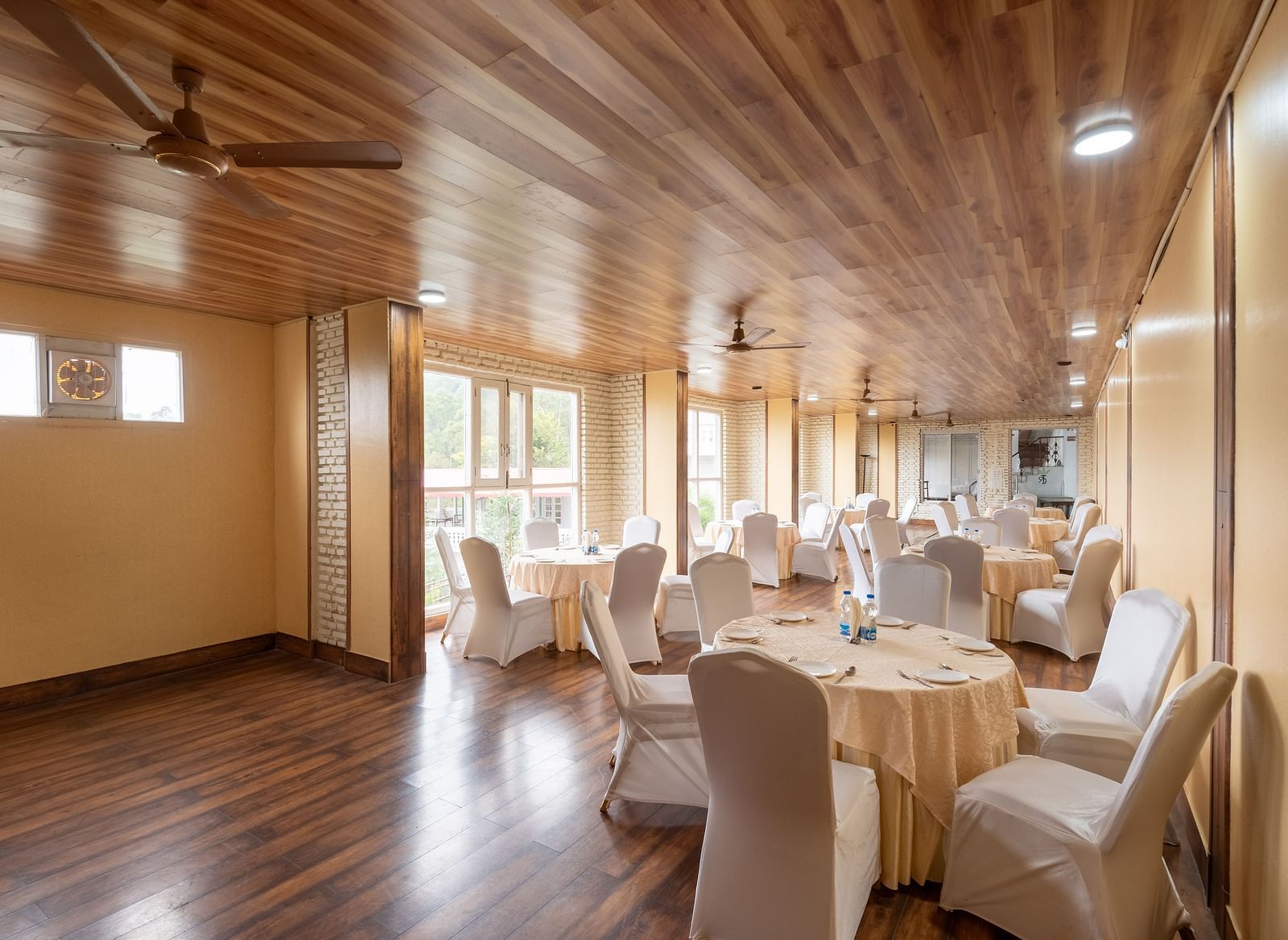 Well-lit banquet hall at DLS Tehri Club Resort with tables and chairs set for a meeting or event
